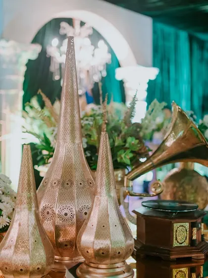 A collection of decorative items, including perforated copper lanterns and a vintage gramophone, that help build the rich, layered narrative of the event.