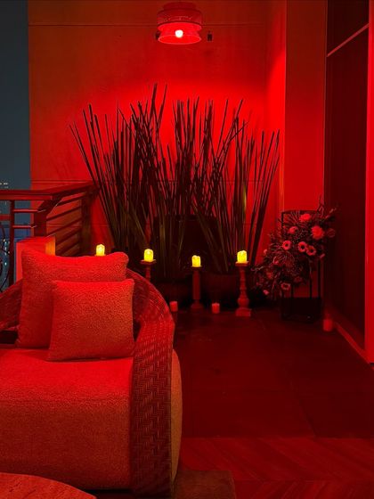 We created a moody and dramatic vibe on this balcony with bold red lighting. The silhouettes of the tall plants and the glow of the candles create a unique and intimate lounge space.