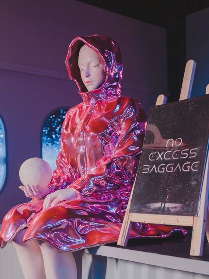 A surreal decor piece featuring a chrome mannequin with a sign reading "No Excess Baggage," adding a quirky and artistic touch to the sci-fi theme.
