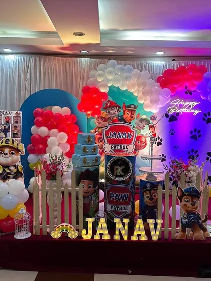 A detailed Paw Patrol setup with character cutouts, a themed cake table, and a large marquee number '1'. The red, blue, and yellow balloon decor perfectly matches the show's colors.