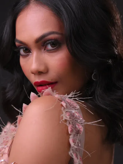 A detailed shot of the shoulder and makeup, highlighting the texture of the dress and the smooth skin finish.