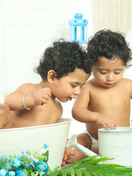 Twin sisters share a tub during a playful bath session. It's a sweet and intimate moment of them playing together.