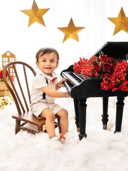 A little musician at his piano. The starry night theme with red and gold accents creates a festive and magical atmosphere for a birthday shoot.