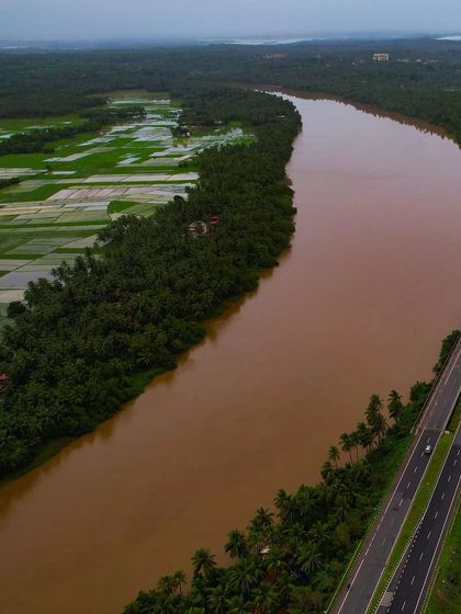 An aerial view of the Souparnika River flowing alongside the highway and Maravanthe beach, a unique geographical feature.