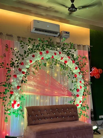 A close-up of the floral arch, made with white flowers, red rose accents, and green leaves.