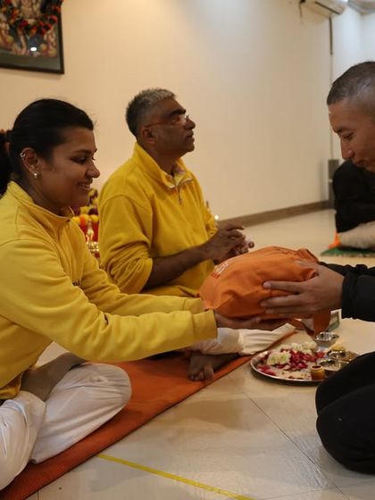 A student receives their welcome kit, wrapped in auspicious saffron cloth, as part of the initiation into the Gurukula system.