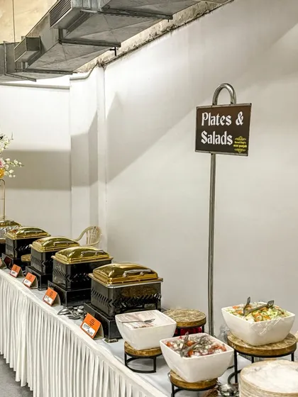 A long shot of our buffet line, ready for service. The elegant setup with golden chafing dishes and fresh salads creates an inviting atmosphere.