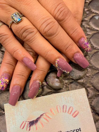 A sophisticated set of mauve-colored coffin nails. The accent nails feature a cascade of gold glitter and multi-colored flakes for a touch of celebration.