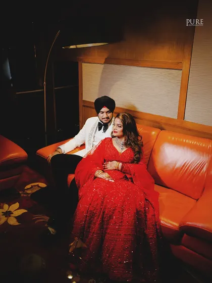 A cozy and intimate moment on the couch during the reception party. The warm lighting adds to the romantic atmosphere of the shot.