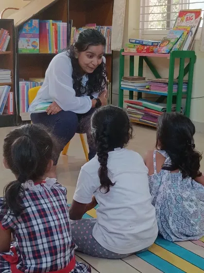 A storyteller leans in to share a secret from the story about Leela the butterfly. This intimate setting helps even the youngest children feel connected and engaged.