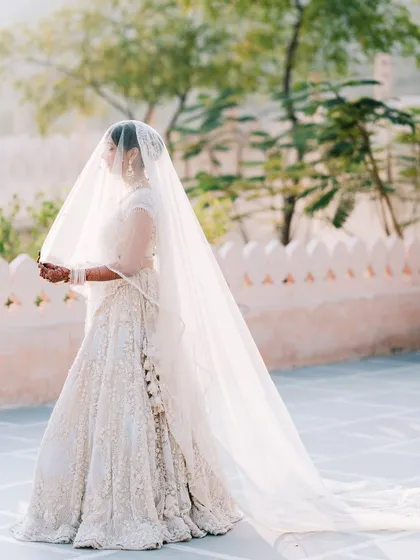 A breathtaking bridal portrait with a long, flowing veil. This shot is all about grace and elegance, creating a timeless and dramatic image against the Pushkar landscape.
