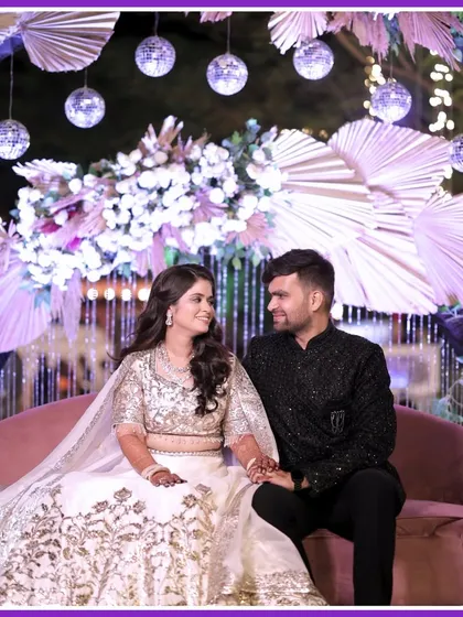 A dreamy Sangeet portrait. The couple looks elegant against a boho-chic backdrop with pampas grass and disco balls.