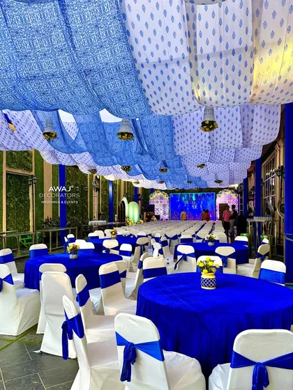 The guest seating area for the Haldi, with blue and white decor, set under a canopy of patterned drapes.
