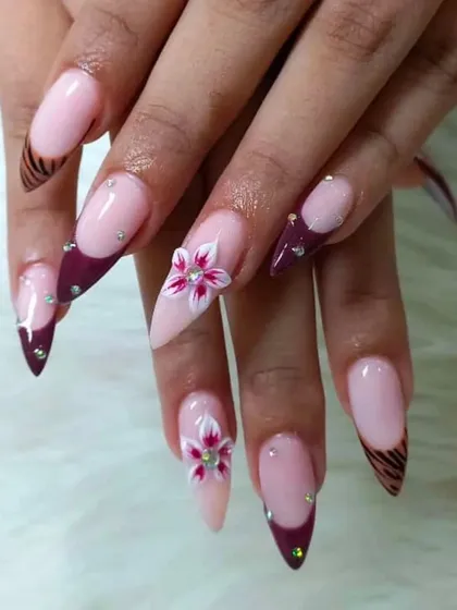 We specialize in 3D nail art. Here, we've combined a sharp stiletto shape with intricate, hand-sculpted acrylic flowers and sparkling rhinestones for a truly custom design.