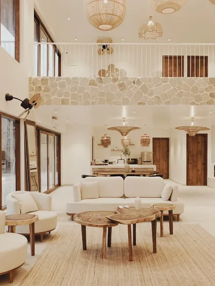 This angle shows the mezzanine level overlooking the main living space, a design choice that maintains a sense of connection and openness. The use of natural stone on the pillars and mezzanine wall adds texture and an earthy feel.