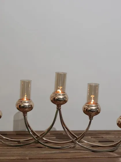 The Vesper Quintet, our stunning 5-tube candelabra. Its elegant, curved design and rose-gold finish make it a dramatic centerpiece that brings a warm, ambient glow to any dinner party.