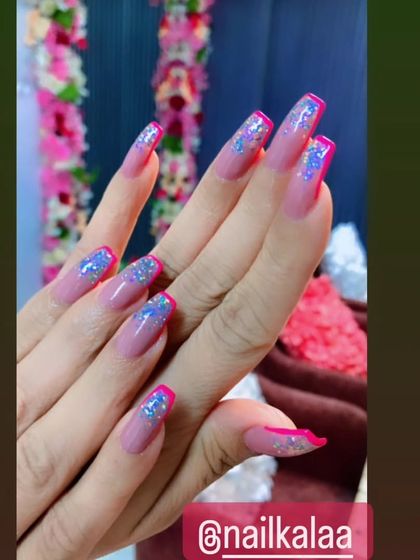 A glamorous French manicure with a twist, featuring long pink nails with sparkling glitter tips.