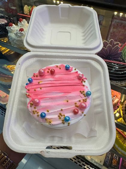 A colorful bento cake with pink frosting and bright sprinkles. This mini cake is all about fun and joy, perfect for a cheerful, spontaneous treat.