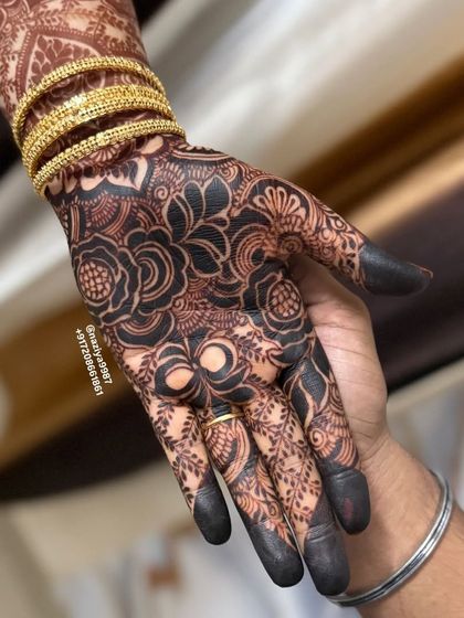 A close-up of the hand with the fresh, dark henna paste.