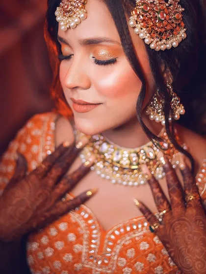 A close-up focusing on the shimmering eye makeup and intricate jewelry, with warm, soft lighting.