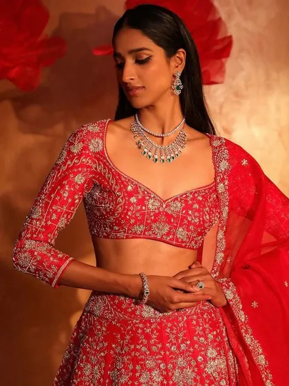 A classic red lehenga with silver embroidery. The sweetheart neckline and full sleeves make it a regal and timeless choice for a bride.
