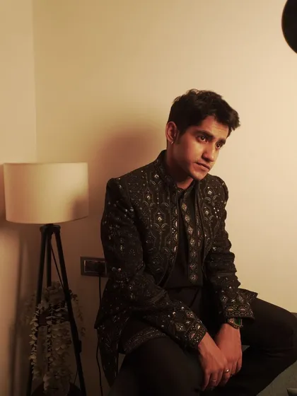 A stylish, moody shot of Ahsan Vazir in our black embroidered jacket set, proving that traditional wear can be incredibly modern and cool.