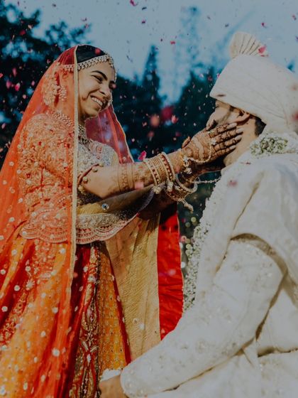The bride playfully holds the groom's face after the Varmala exchange, a moment of pure affection.