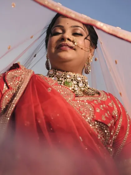 An artistic shot of the bride looking up through her veil, showcasing her beautiful eye makeup and the grandness of her choker.
