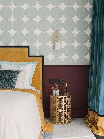 A minimal headboard paired with a highlighter texture paint on the wall gives an excellent look. This design uses a bold color block and a patterned wallpaper to create a vibrant and modern bedroom.
