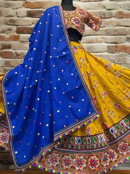 This vibrant yellow lehenga features traditional Gujarati embroidery and a contrasting blue dupatta dotted with mirrors, perfect for a sunny and joyful Garba look.