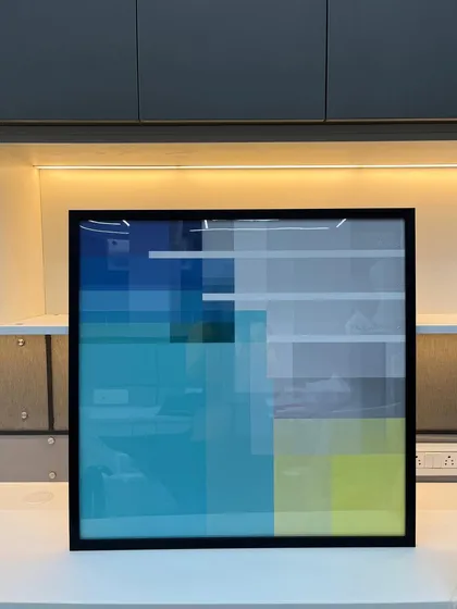 A framed abstract geometric painting with cool tones of blue and yellow, ready to be hung in a modern office space.