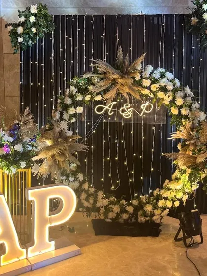 A personalized photo booth for a Sangeet night. The floral ring, custom initial lighting, and fairy light curtain create a perfect spot for guests to take pictures.