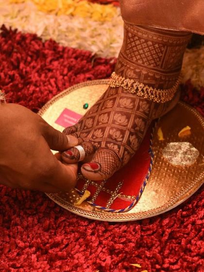 A beautiful shot of a bride's feet during a wedding ritual. The design features a lotus grid pattern, which looks stunning with traditional anklets.