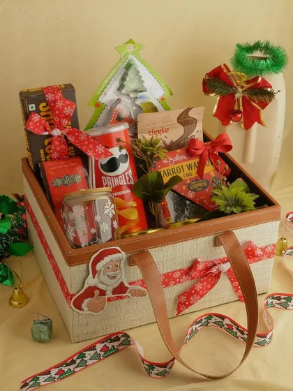 A closer look at the Christmas foodie hamper. This jute bag with leather handles is filled with Pringles, cake, hot chocolate mix, and other festive snacks.