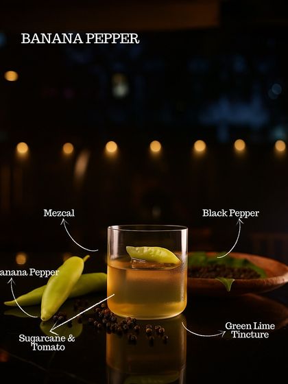The Banana Pepper cocktail, an inventive mix of mezcal, banana pepper, sugarcane, tomato, and green lime tincture. A sweet, spicy, and savory delight.