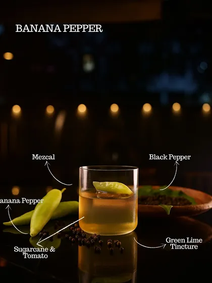 The Banana Pepper cocktail, an inventive mix of mezcal, banana pepper, sugarcane, tomato, and green lime tincture. A sweet, spicy, and savory delight.