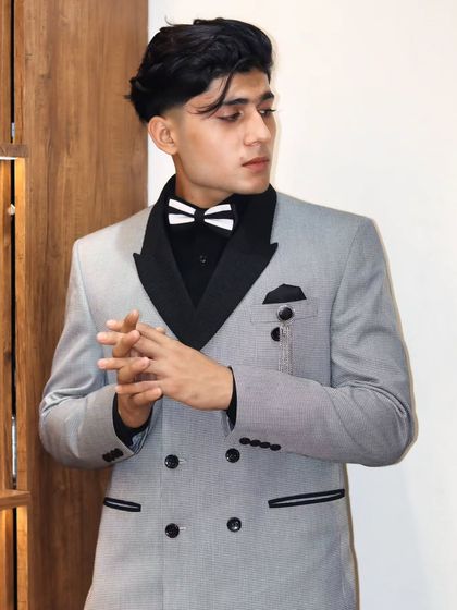 A double-breasted suit that combines classic tailoring with a modern edge. The contrasting black lapels and striped bow tie add a playful yet sophisticated touch to the pinstripe jacket.