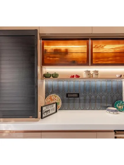 In this kitchen, we focused on creating a clean look with smart functionality. The design features a black rolling shutter to neatly hide appliances, while the backlit cabinets with sunset-hued glass add warmth and ambiance. This combination of practical storage and aesthetic detail makes the kitchen both efficient and stylish.