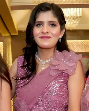 A client looking pretty in a pink gown-style saree for a party. The makeup is soft and feminine.