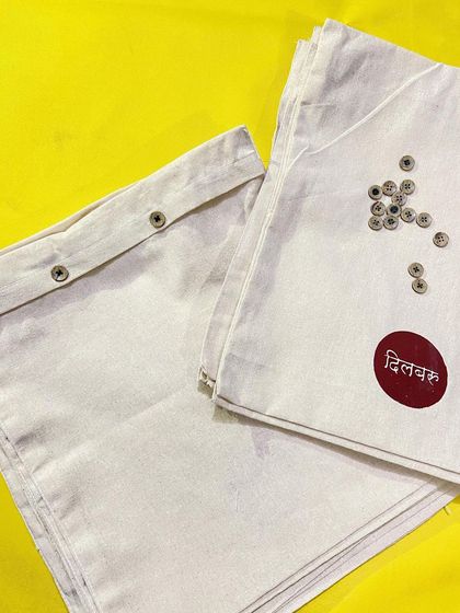 A closer look at the 'Dilbaru' garment bags. The bold, circular logo is screen printed for a lasting finish, and the button closure keeps the contents secure. This is packaging designed to be kept and reused.