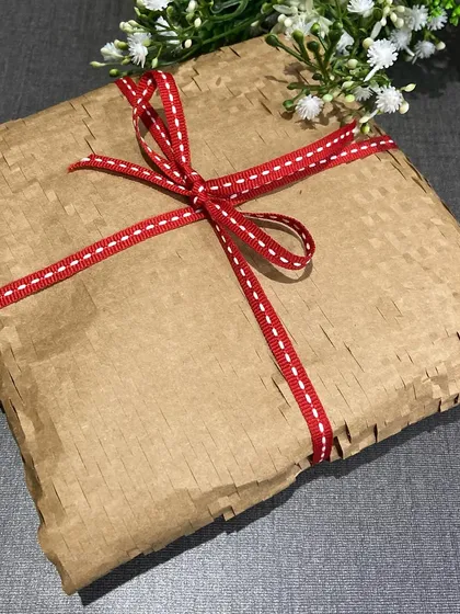 A simple gift wrapped in brown paper becomes instantly special with a festive red and white stitched ribbon. The right ribbon makes all the difference.