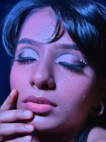 Under purple and pink lighting, the shimmer on the eyelids becomes more prominent, showcasing the dynamic quality of the makeup.