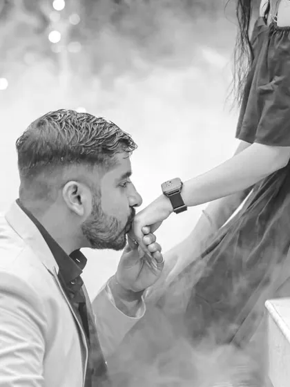 A chivalrous and tender moment captured in classic black and white. The groom kissing the bride's hand is a timeless gesture of love, made even more powerful by the dramatic, smoky background.