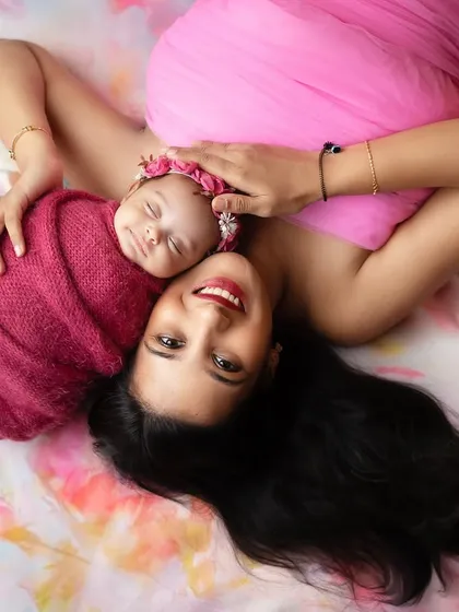 A beautiful overhead shot of a mother and her newborn daughter, lying on a bed of flowers. This artistic composition celebrates the beauty of motherhood.
