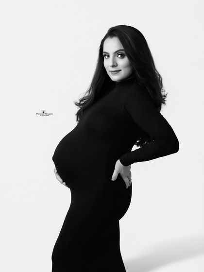 A classic black and white maternity portrait. The simple side profile pose is elegant and timeless, beautifully showcasing the baby bump.