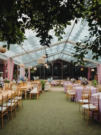 A clear-top tent allows guests to dine under the stars, with elegant table settings and hanging lanterns.