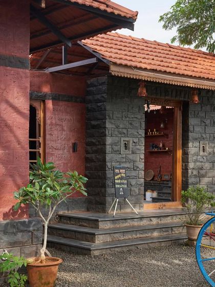 The entrance to the restaurant features a mix of red earth walls and black stone, creating a rustic and authentic feel.