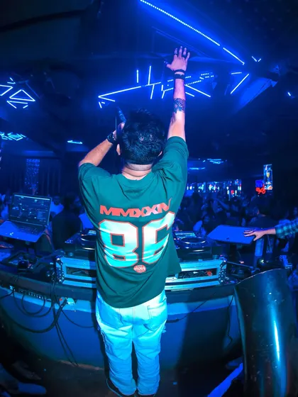 A shot from behind, showing me hyping up the crowd at Club Illusions. The neon blue lighting adds to the futuristic feel of the club.