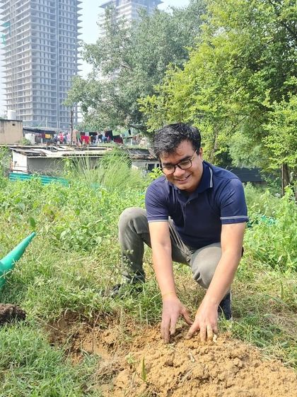 A smiling volunteer from NatWest gets his hands in the soil at Ghata Bundh. Their team planted 625 native saplings to help restore this historic embankment's water catchment capacity.