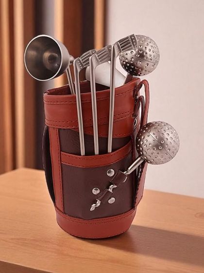 A close-up of the Golf Miniature Bar Kit, showing the detailed golf club and ball designs on the stainless steel bar tools, held in a premium leather-like caddy.